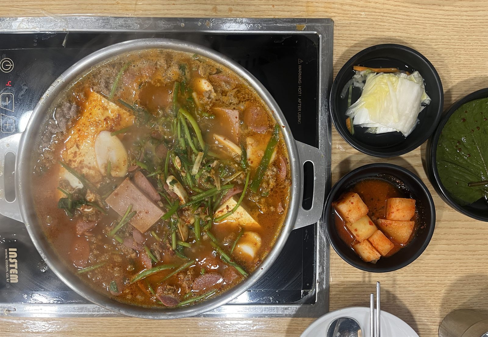 대우부대찌개 클로즈업 — 얇게 썬 햄과 소시지가 자작한 국물 위에 올라간 모습