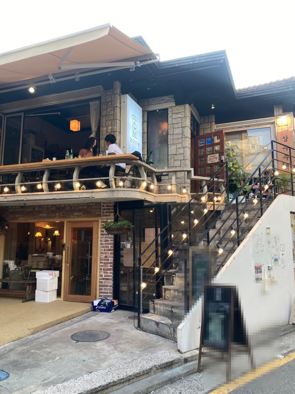 상수주택 입구 — 오래된 주택 2층으로 올라가는 계단, 입간판에 메뉴가 적혀 있습니다