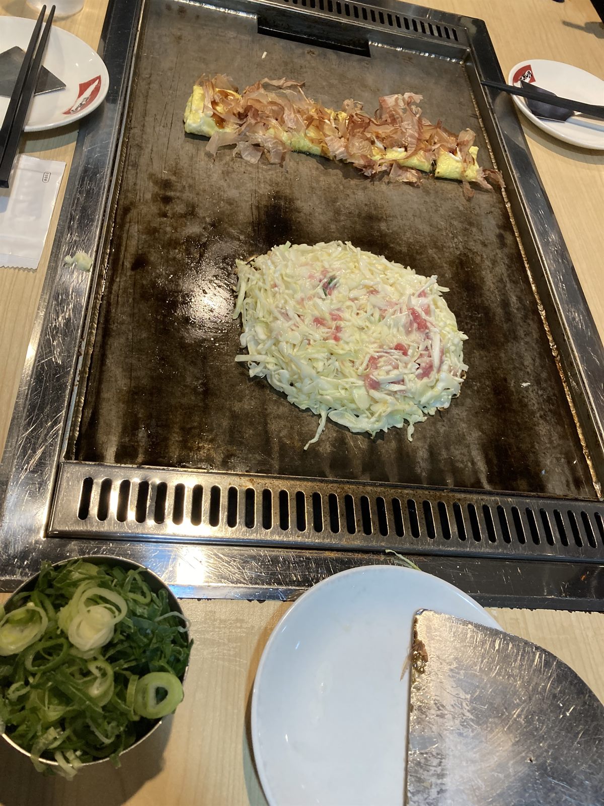 철판 위에서 구워지는 오코노미야끼와 옆에 놓인 계란말이